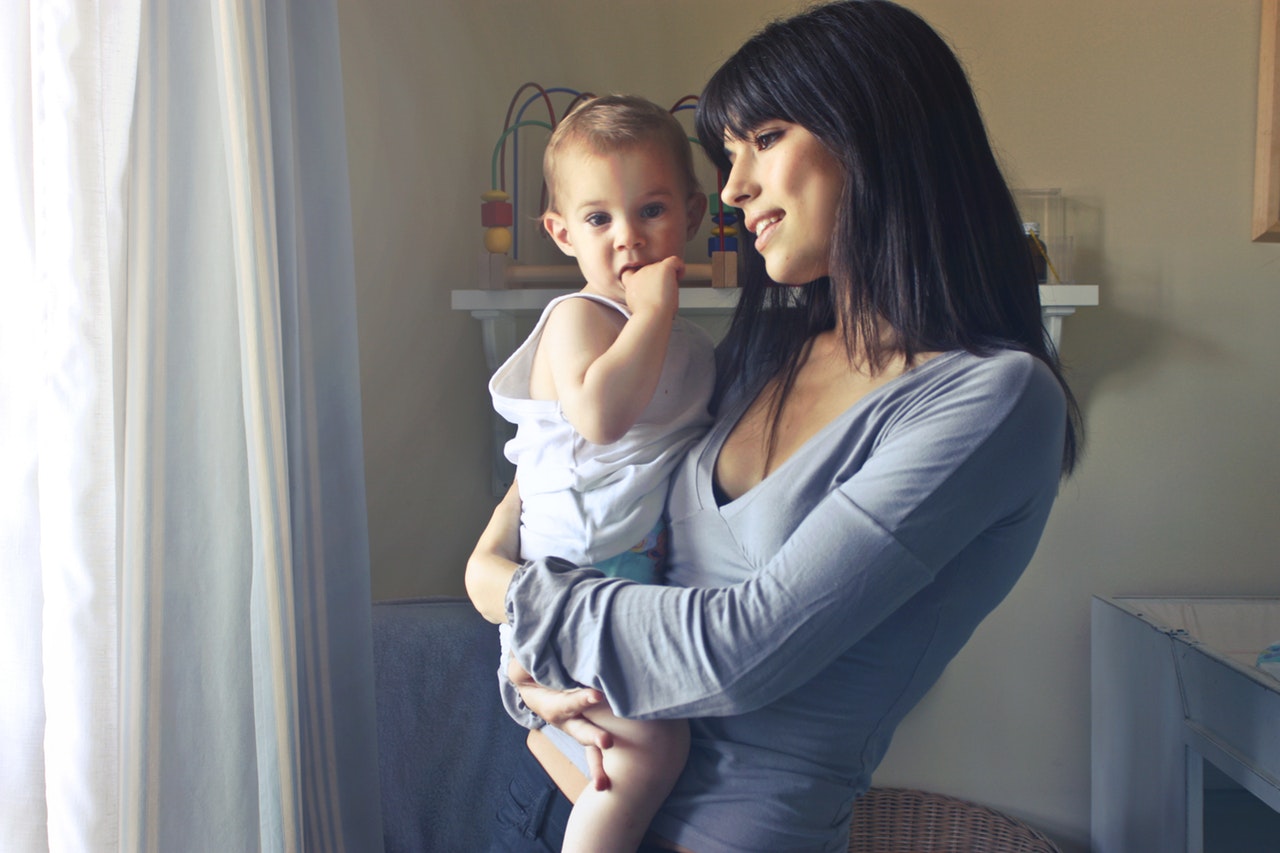 mother and baby standing by window in daylight